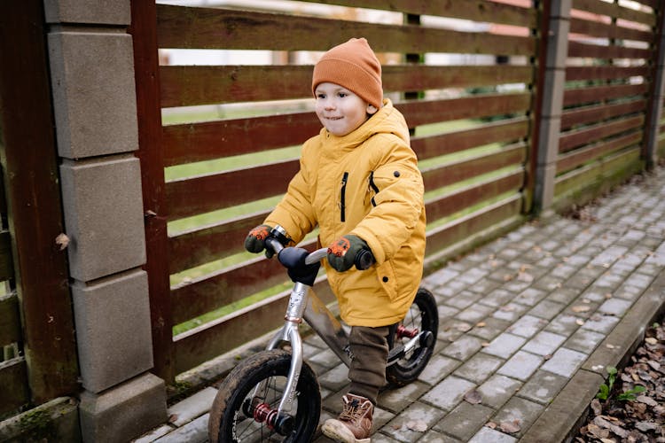 A Child Wearing A Yellow Jacket Riding A Bicycle