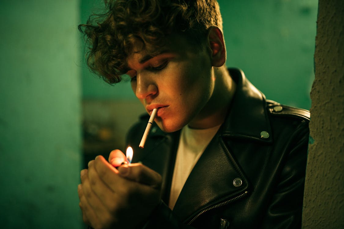Man in Black Leather Jacket Lighting a Cigarette