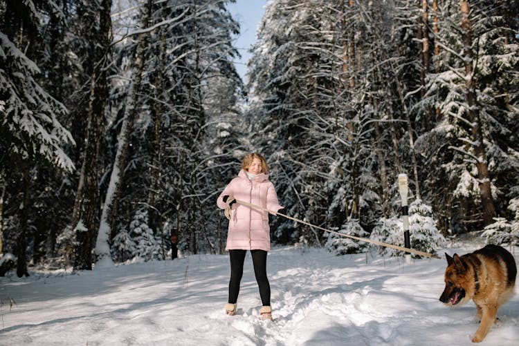 Woman In Pink Jacket Holding The Leash Of A Dog