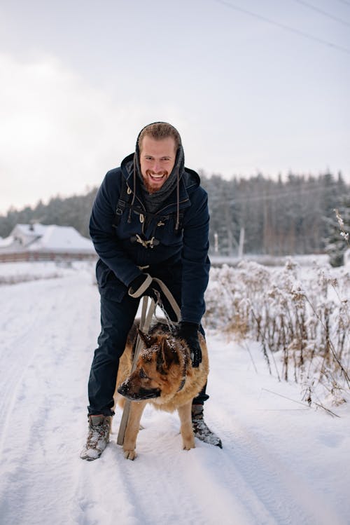 Smiling Man with a Dog on a Walk in Winter and Forest in Background