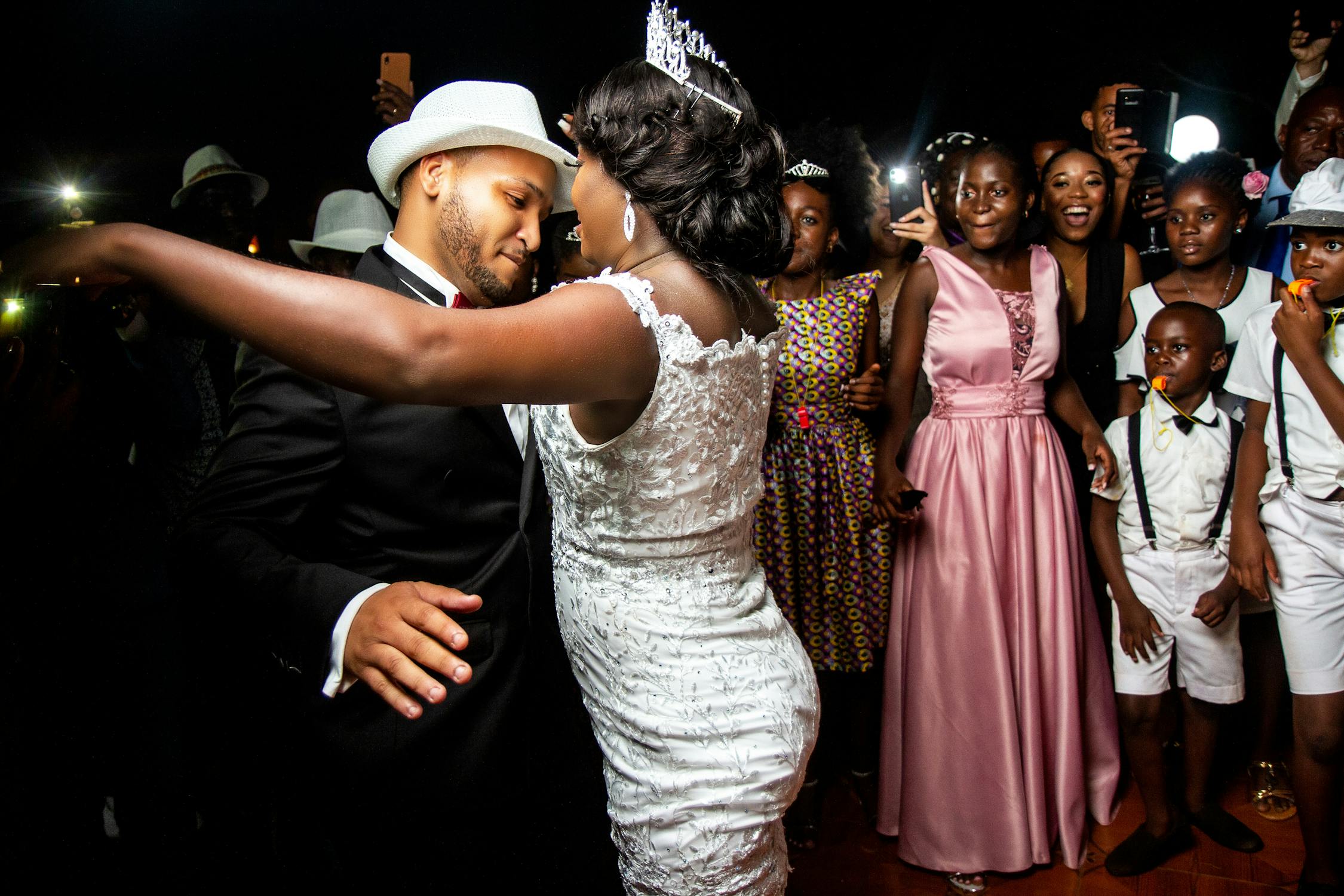 bride and groom dancing in front of guests at nighttime rooftop wedding reception