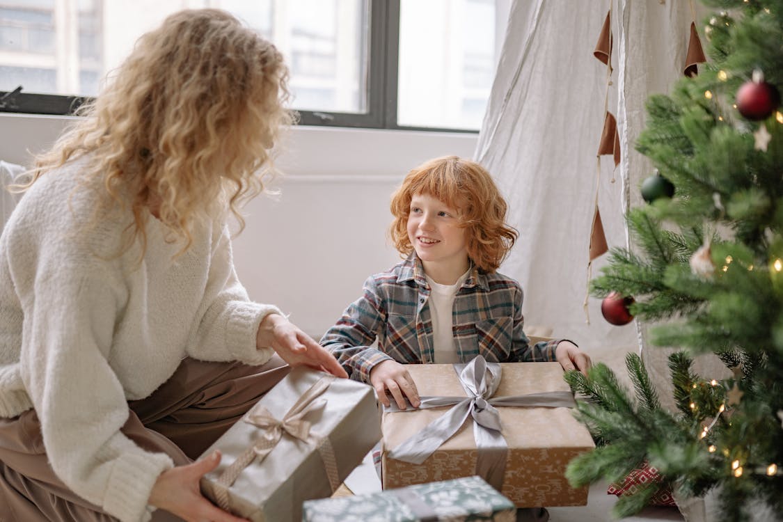 Free A Boy Holding a Present with his Mom on Christmas Stock Photo