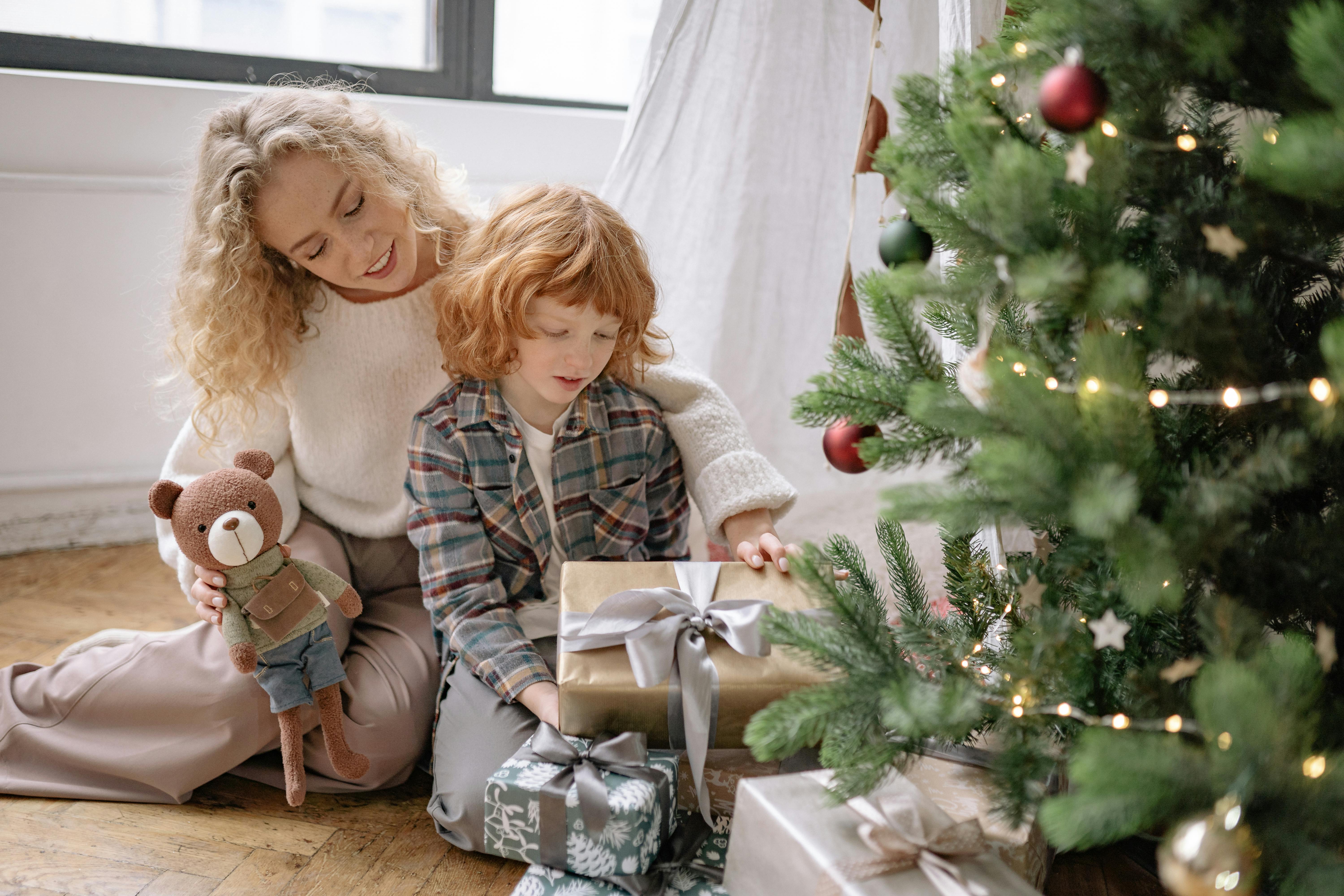 a woman and her son sitting by a christmas tree