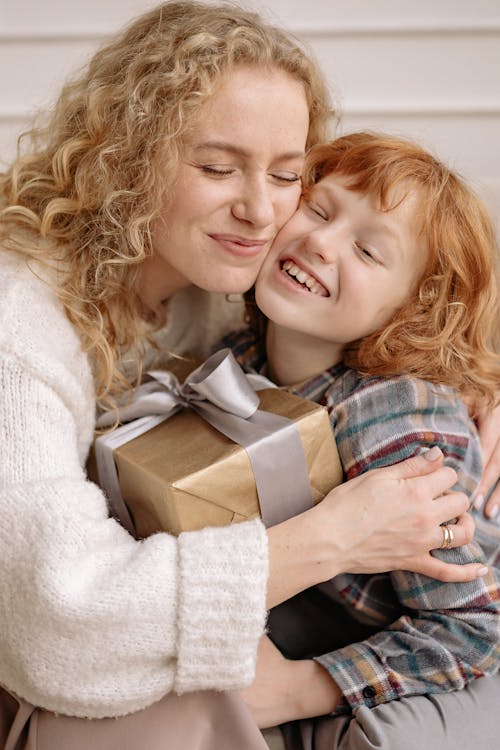 Free A Woman and a Boy Holding a Gift Box While Hugging Each Other Stock Photo