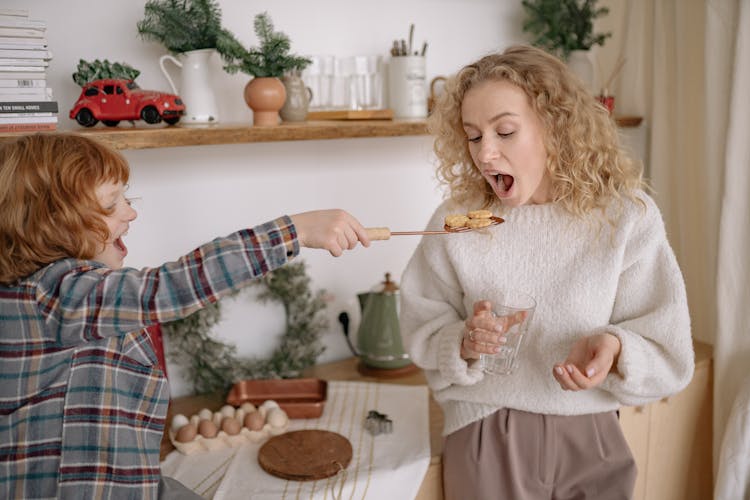 A Boy Giving A Woman A Ladle With Biscuits 