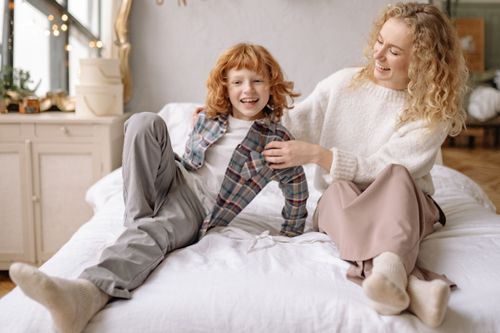 Free A happy mother and son playing together on the bed, smiling joyfully indoors. Stock Photo