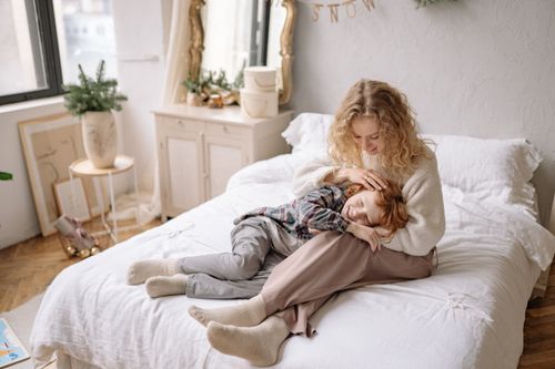 Free Mother and son sharing a tender moment in a beautifully decorated bedroom setting. Stock Photo
