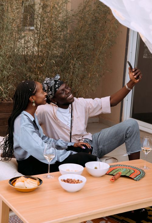 Free Smiling couple taking a selfie while enjoying a casual outdoor brunch with snacks and drinks. Stock Photo