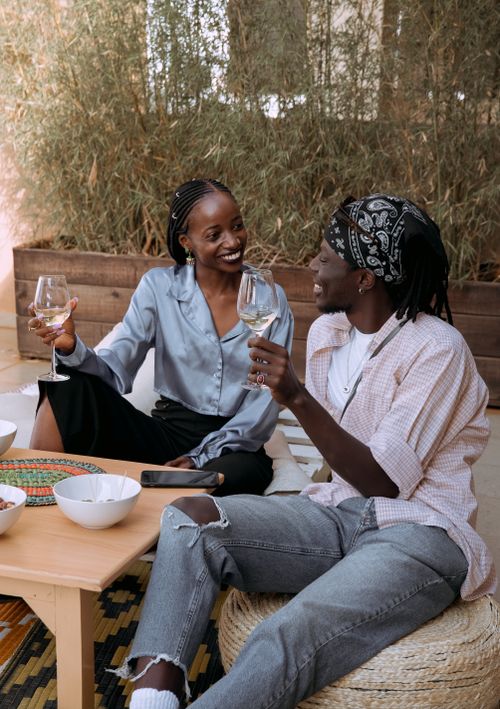 Free Two friends enjoying a casual indoor gathering with wine and conversation. Stock Photo