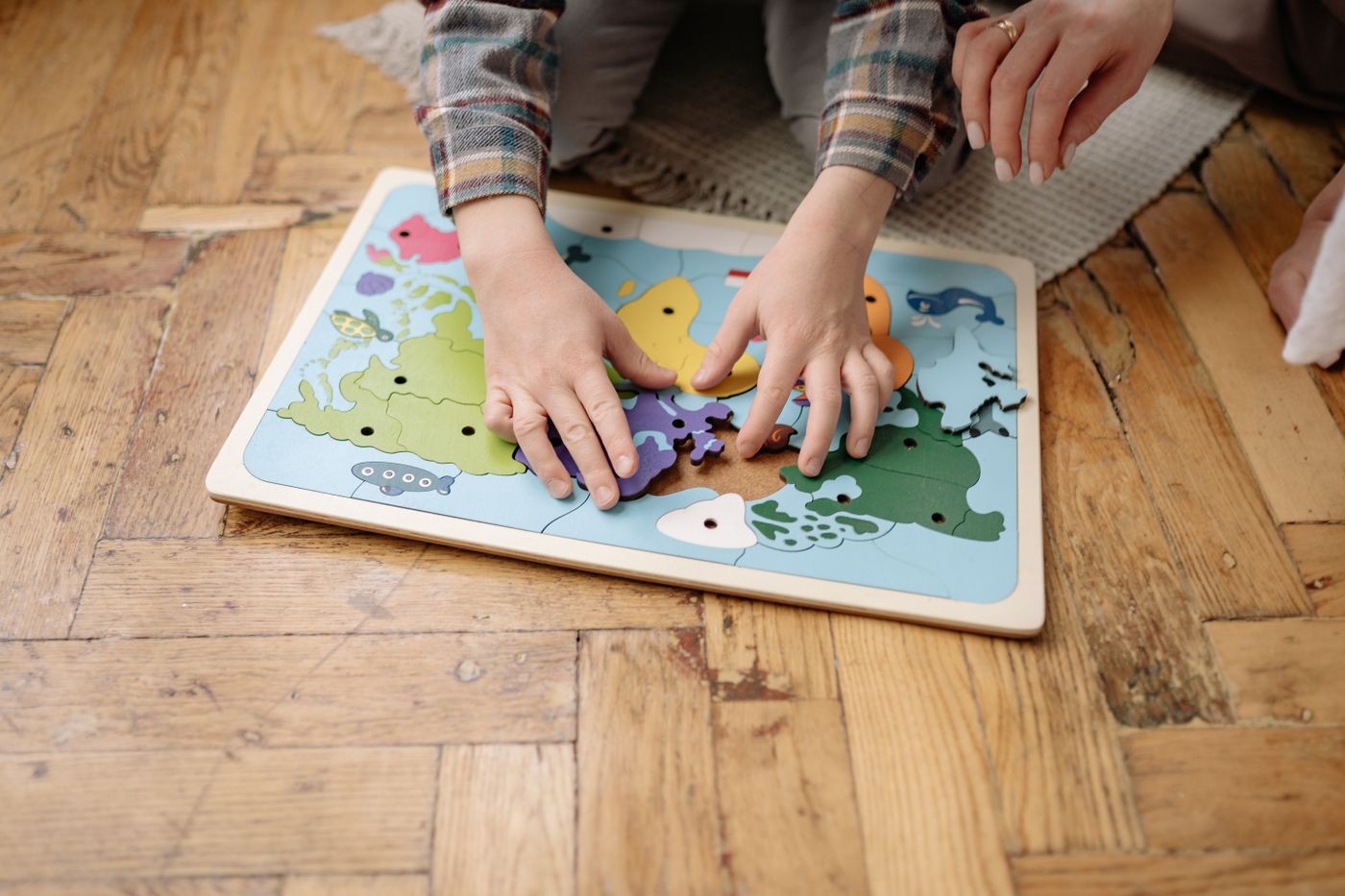 Child assembling colorful educational puzzle pieces on the floor during hands-on learning play