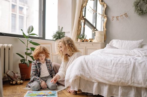 Free A mother and son enjoying quality time together in a cozy bedroom with natural light. Stock Photo