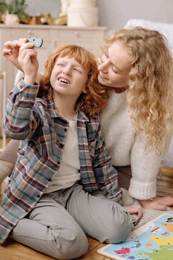 A Woman and a kid Sitting Together on the Floor Holding an Object with a Hole