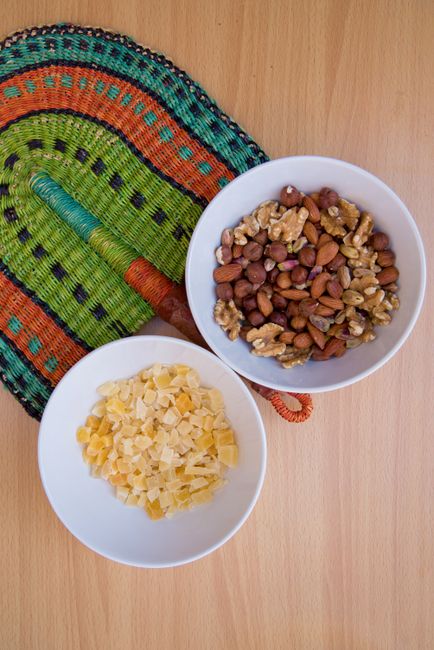 Incorporate dry fruits into daily diet - Simple Recipes Using Dry Fruits | Top view of mixed nuts and dried fruits in white bowls on a colorful woven placemat.
