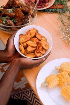A vibrant African meal featuring fried plantains, chicken, and corn on a wooden table.