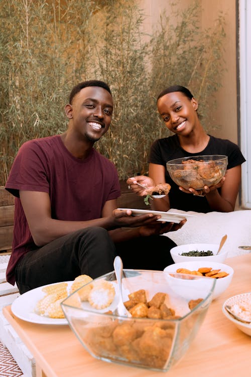 A Man and a Woman Eating Together while Looking at the Camera