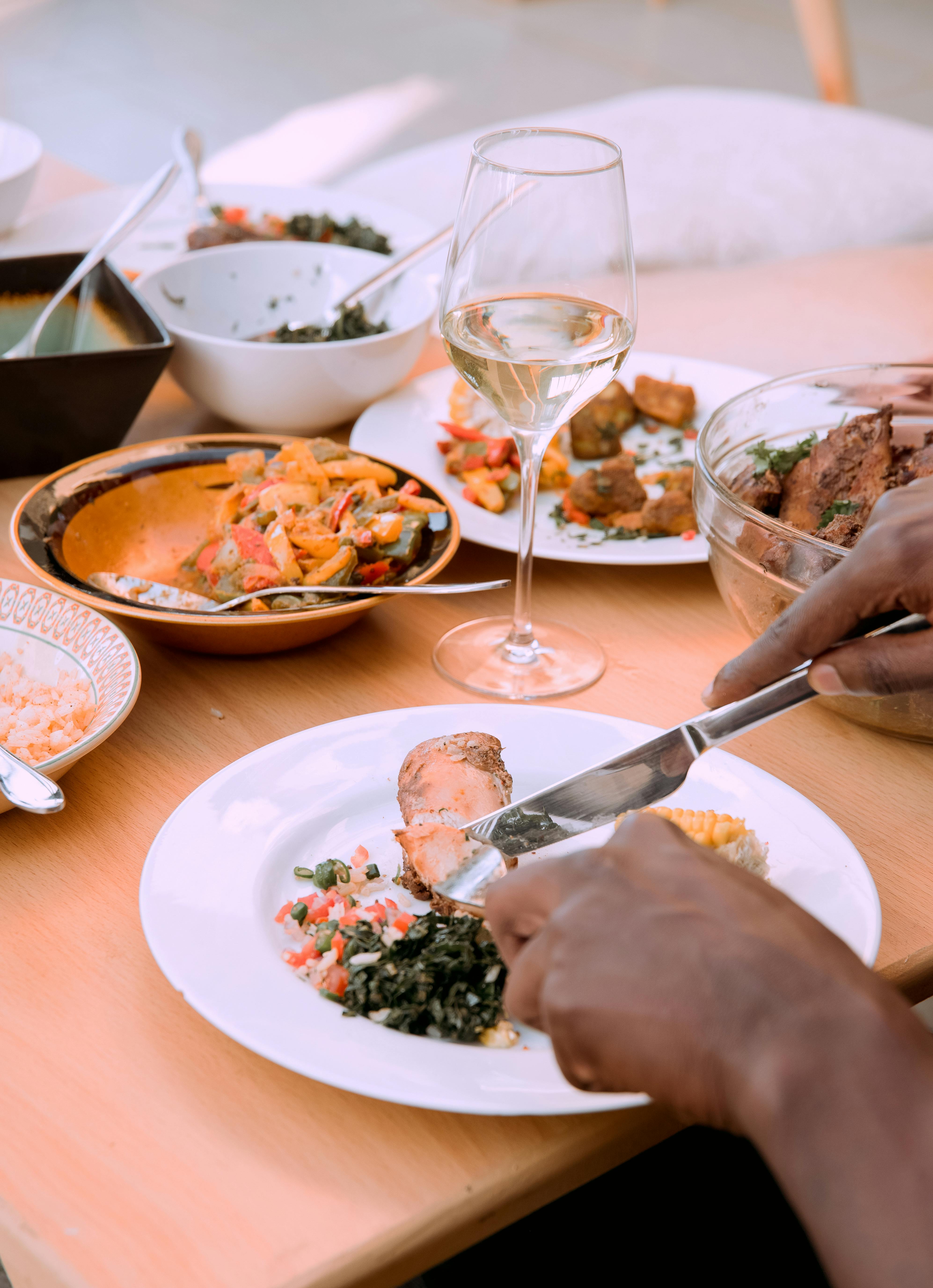 Free Person Cutting Piece of Meat at Dinner Table Stock Photo