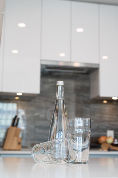 Free Minimalistic kitchen interior featuring a glass bottle and glasses on a counter, ideal for contemporary design themes. Stock Photo