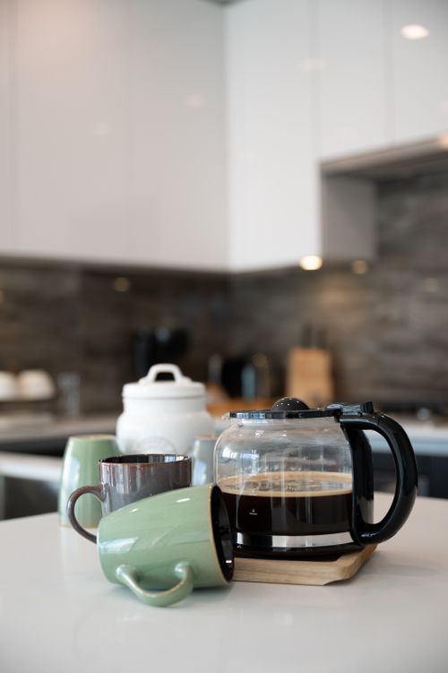 Free Close-up of a modern kitchen counter with a coffee maker and ceramic mugs. Stock Photo