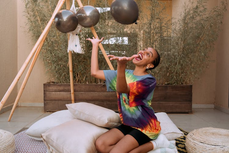 Happy Woman Sitting And Tossing Balloons 