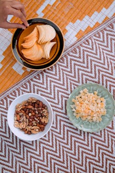 A variety of snacks including chips, nuts, and dried fruits on a patterned blanket.