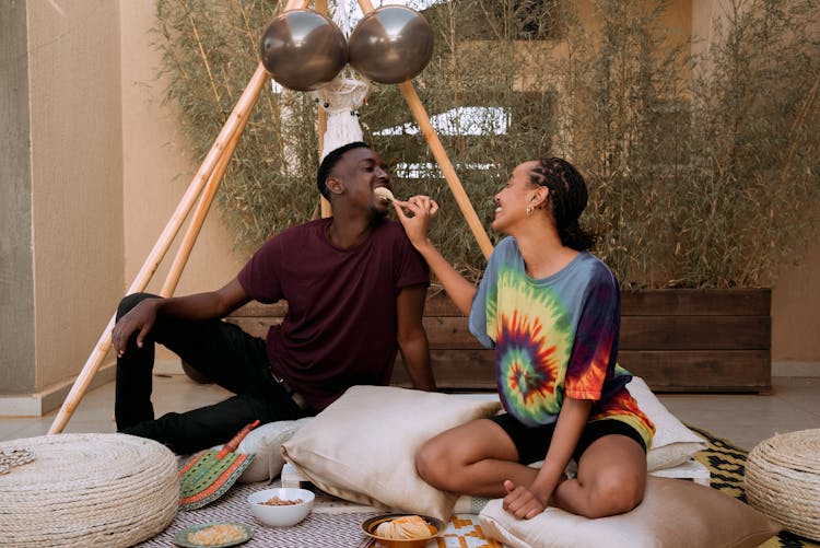 A Woman Feeding A Man A Potato Chip