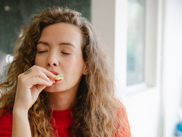 Pleased Woman Biting Tasty Cookie