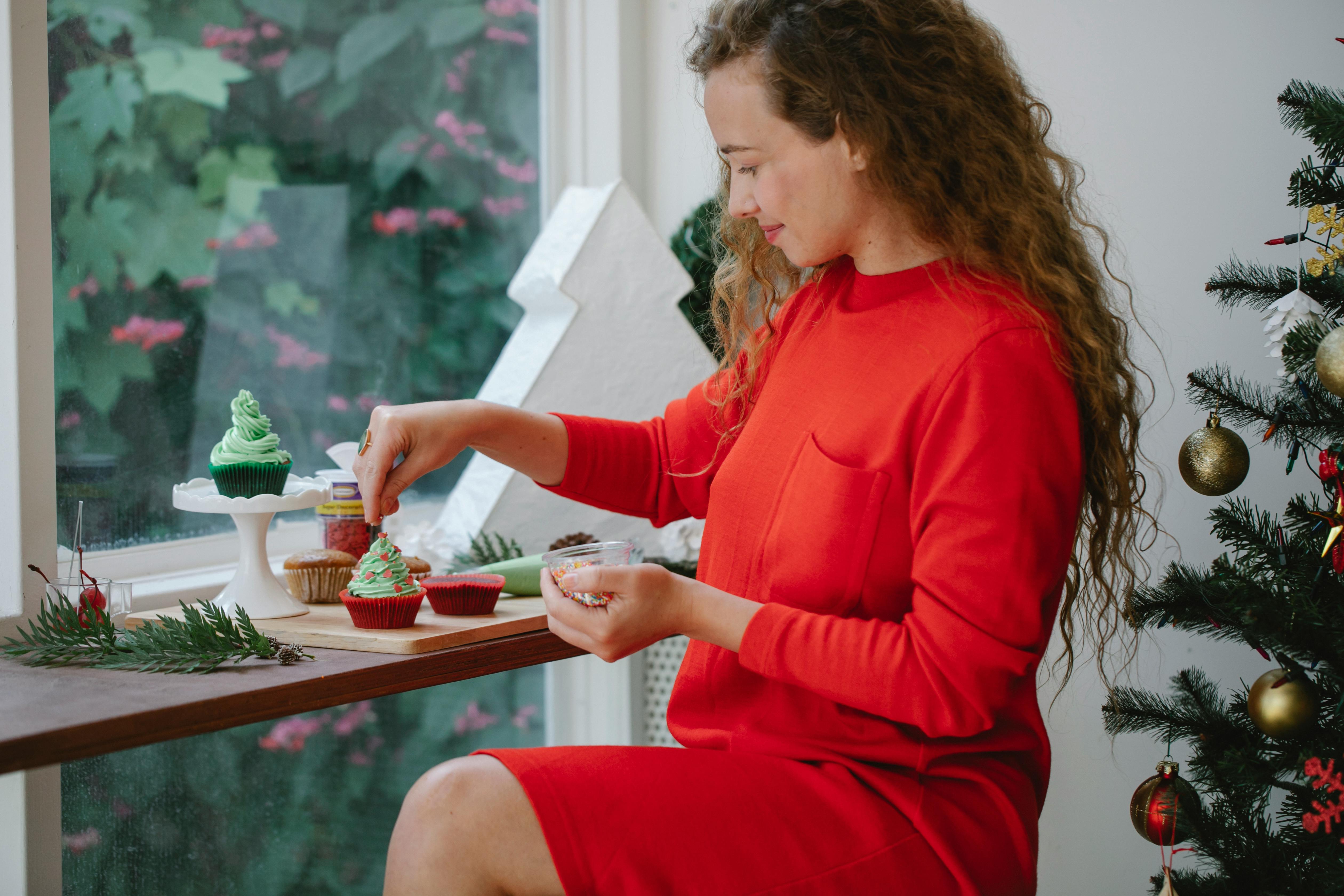 satisfied woman decorating christmas cupcake in cafe