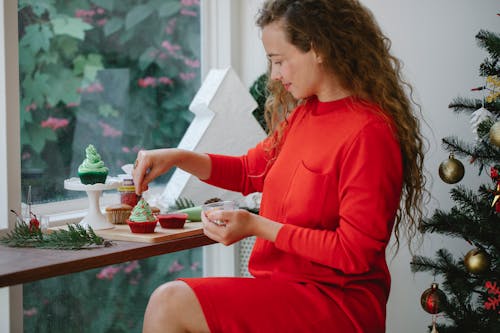 Satisfied woman decorating Christmas cupcake in cafe