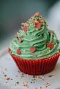 Closeup from above of appetizing sweet cupcake decorated green whipped cream and multicolored sprinkles