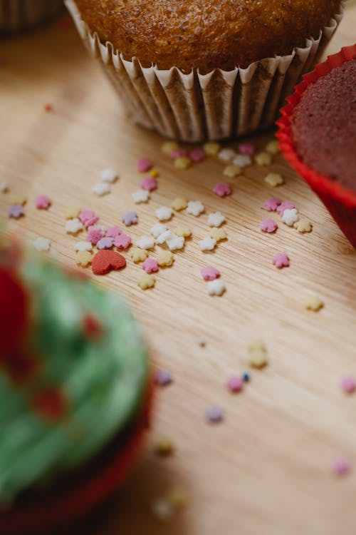 High angle of colourful sugar stars sprinkles for cakes and cupcakes in cases on wooden table