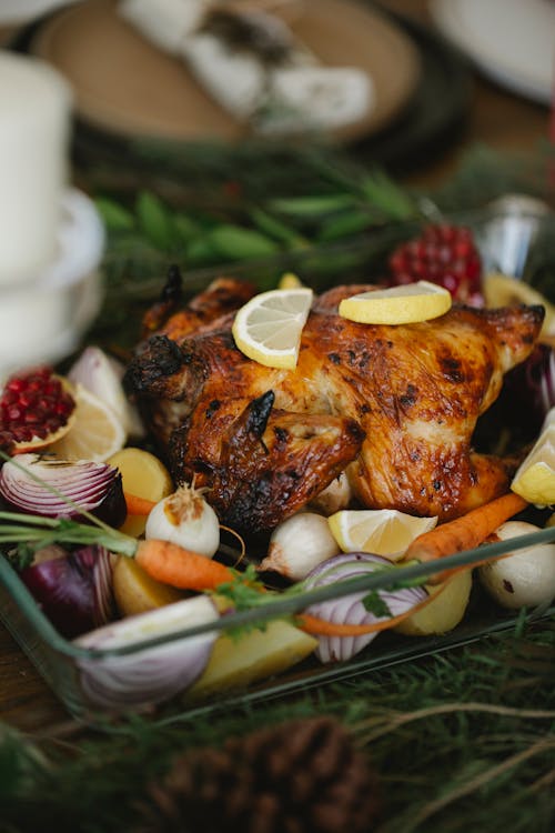 Free Roasted chicken with vegetables in glass roaster on table with fir sprigs Stock Photo