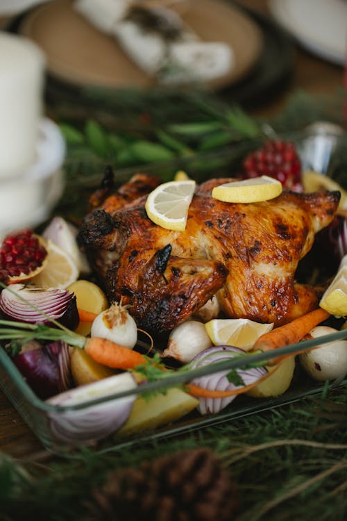 Roasted chicken with vegetables in glass roaster on table with fir sprigs