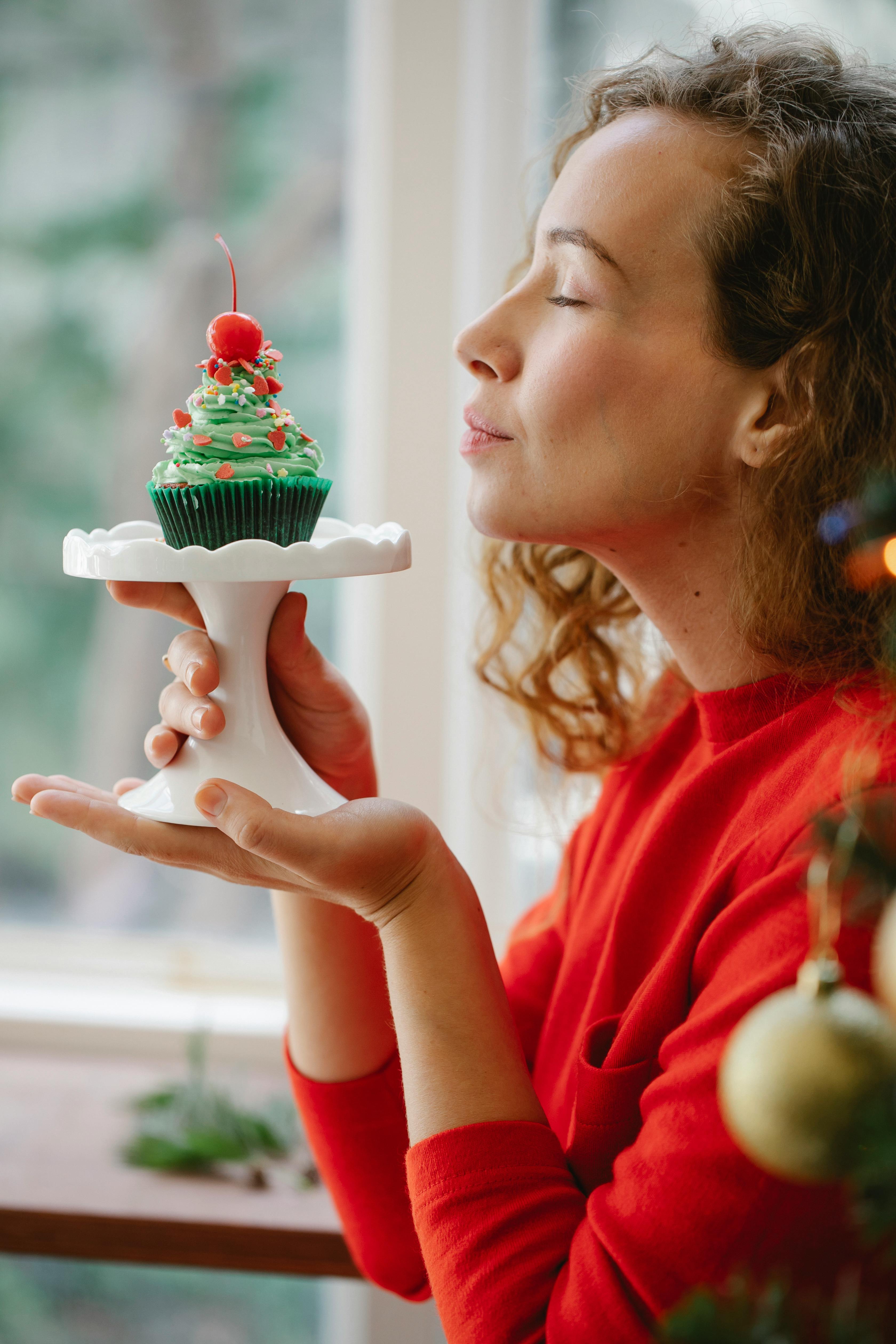 young woman enjoying aroma of cupcake