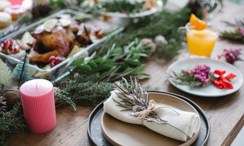 High angle of table served for Christmas dinner with plates with napkins and traditional roasted turkey on glass dish decorated with fir twigs