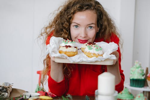 Девушка в красной рубашке с круглым вырезом держит белый торт
