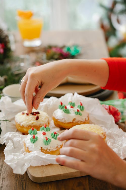 Crop chef decorating delicious doughnuts during New Year holiday