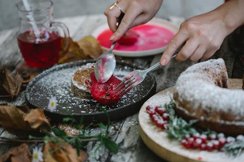 Crop faceless housewife garnishing cake with baked pear