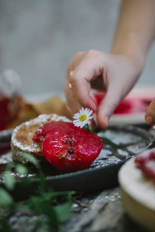 Crop unrecognizable woman decorating pie with chamomile flower