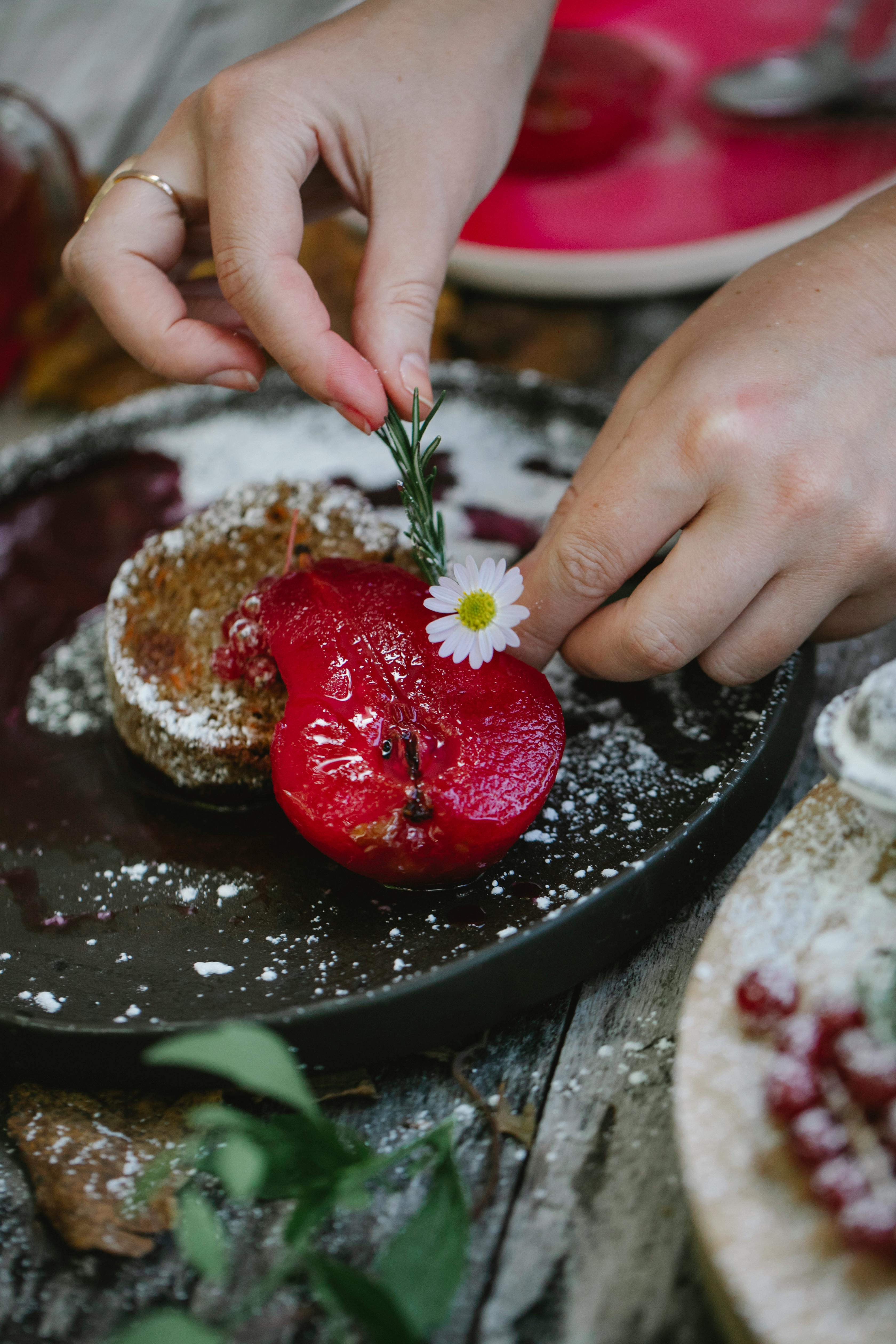 crop anonymous housewife decorating pie with tender chamomile flower