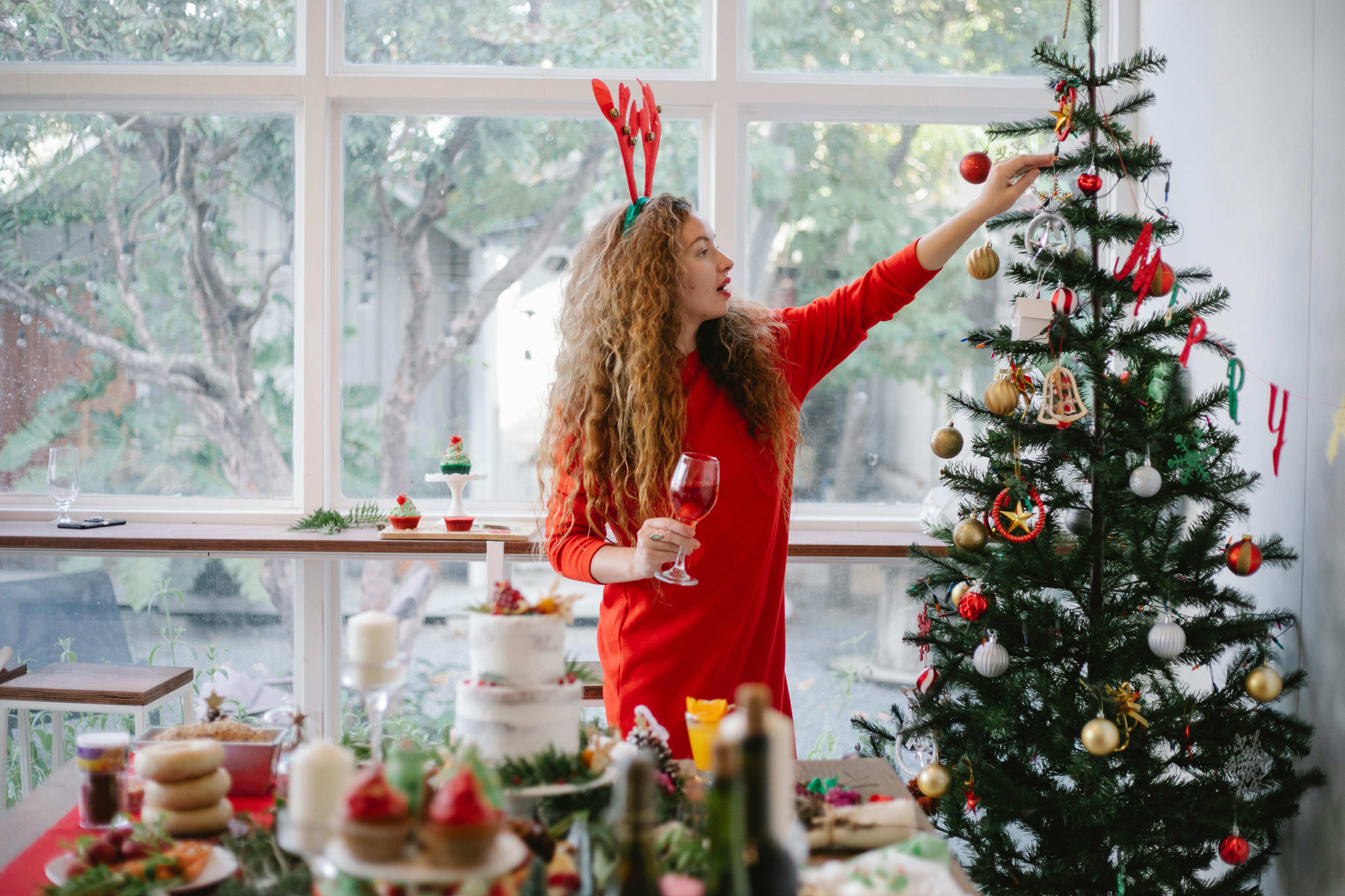 woman in headband with reindeer decorating christmas tree