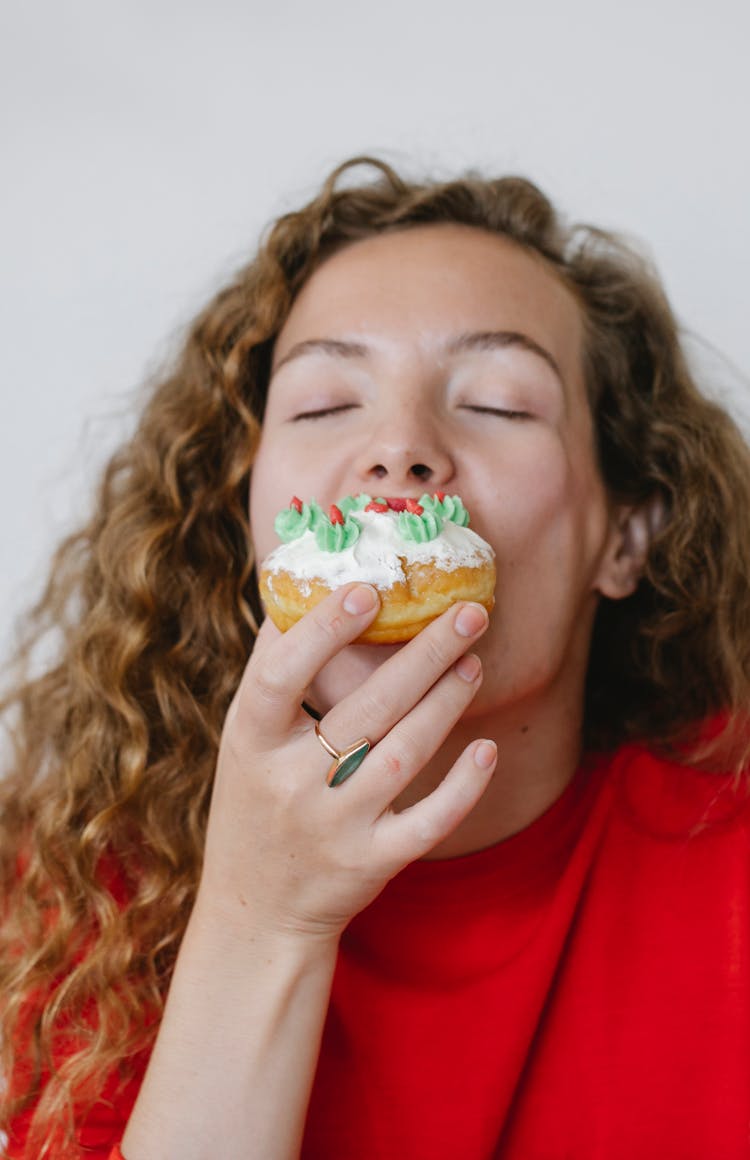 Young Woman Eating Tasty Donut Covered With White Icing