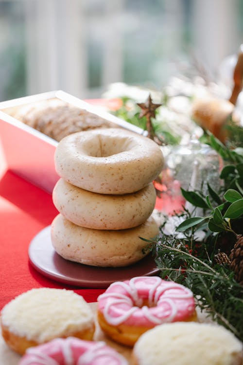 From above of tasty homemade donuts placed near cake and glazed pastry served on table with red tablecloth and green plants for Christmas celebration