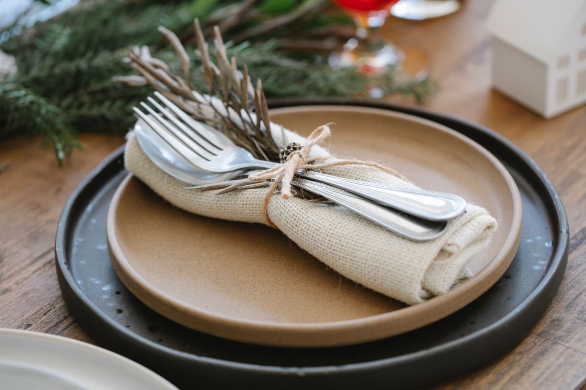 Napkin tied into a bow shape with ribbon on a wooden Christmas table