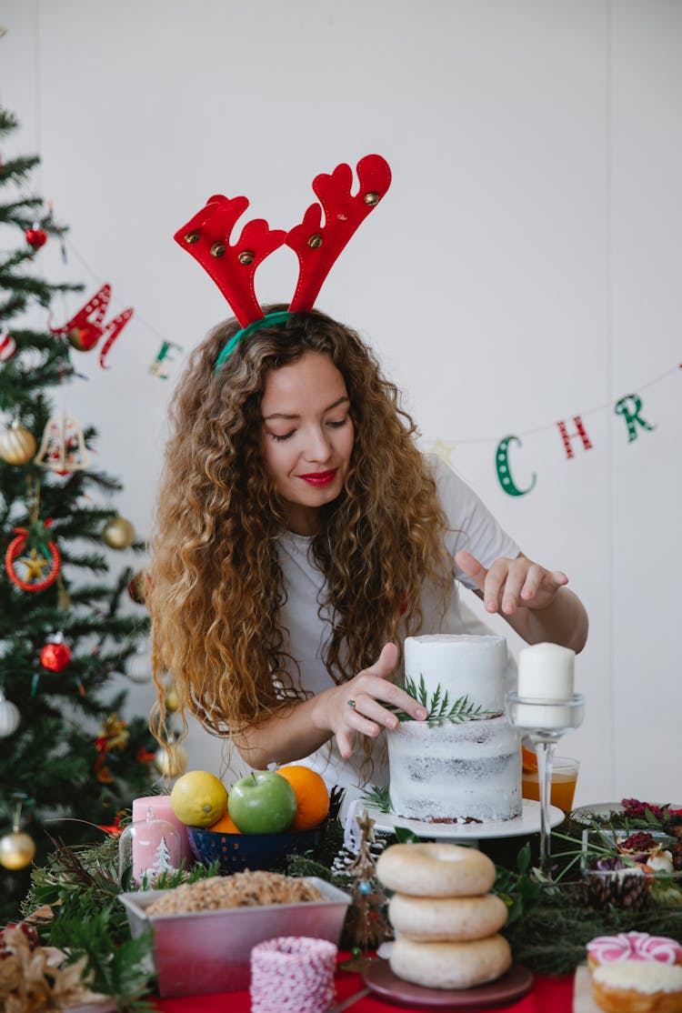 Cute Woman In Reindeer Hat Decorating Christmas Table