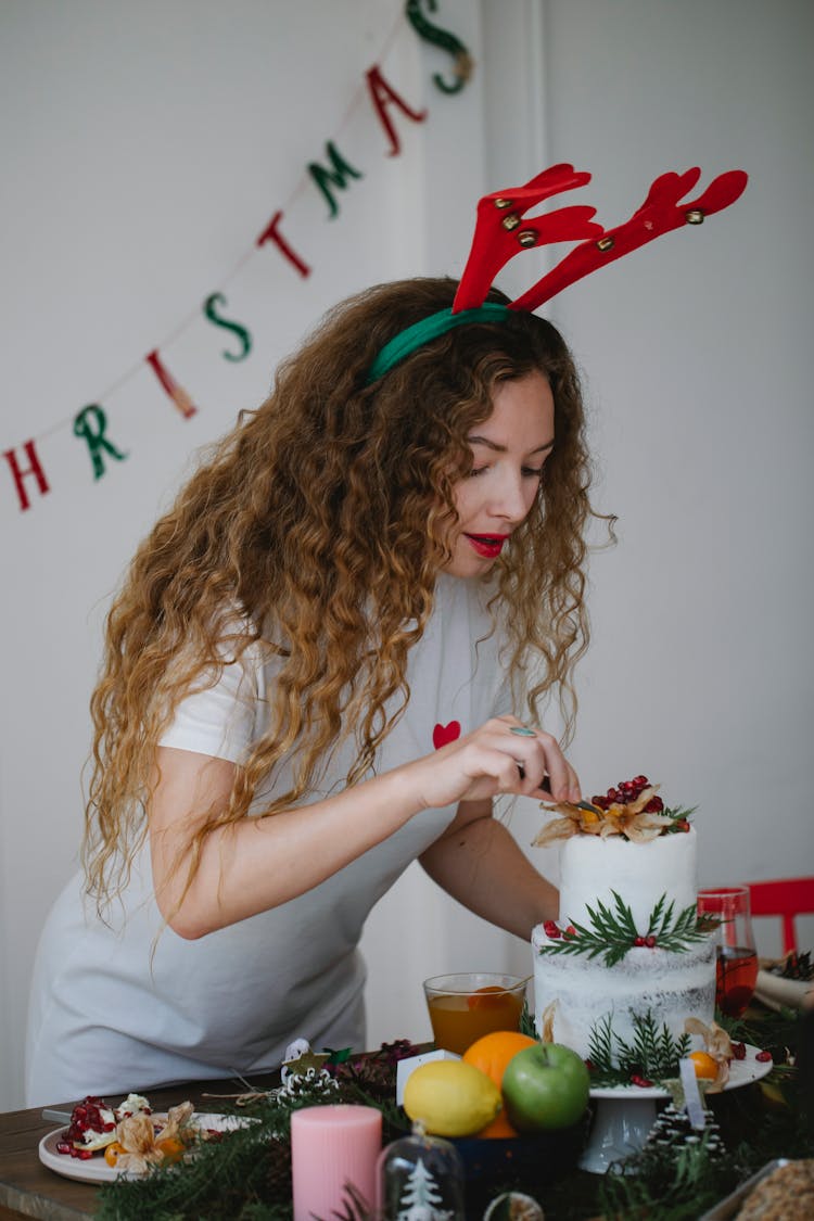 Young Woman Putting Decoration On Top Of Homemade Cake