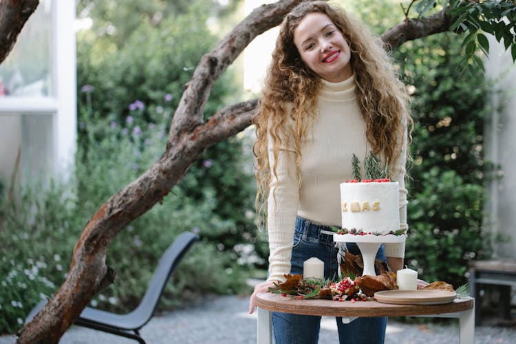 Cheerful Woman With Xmas Cake Standing In Garden