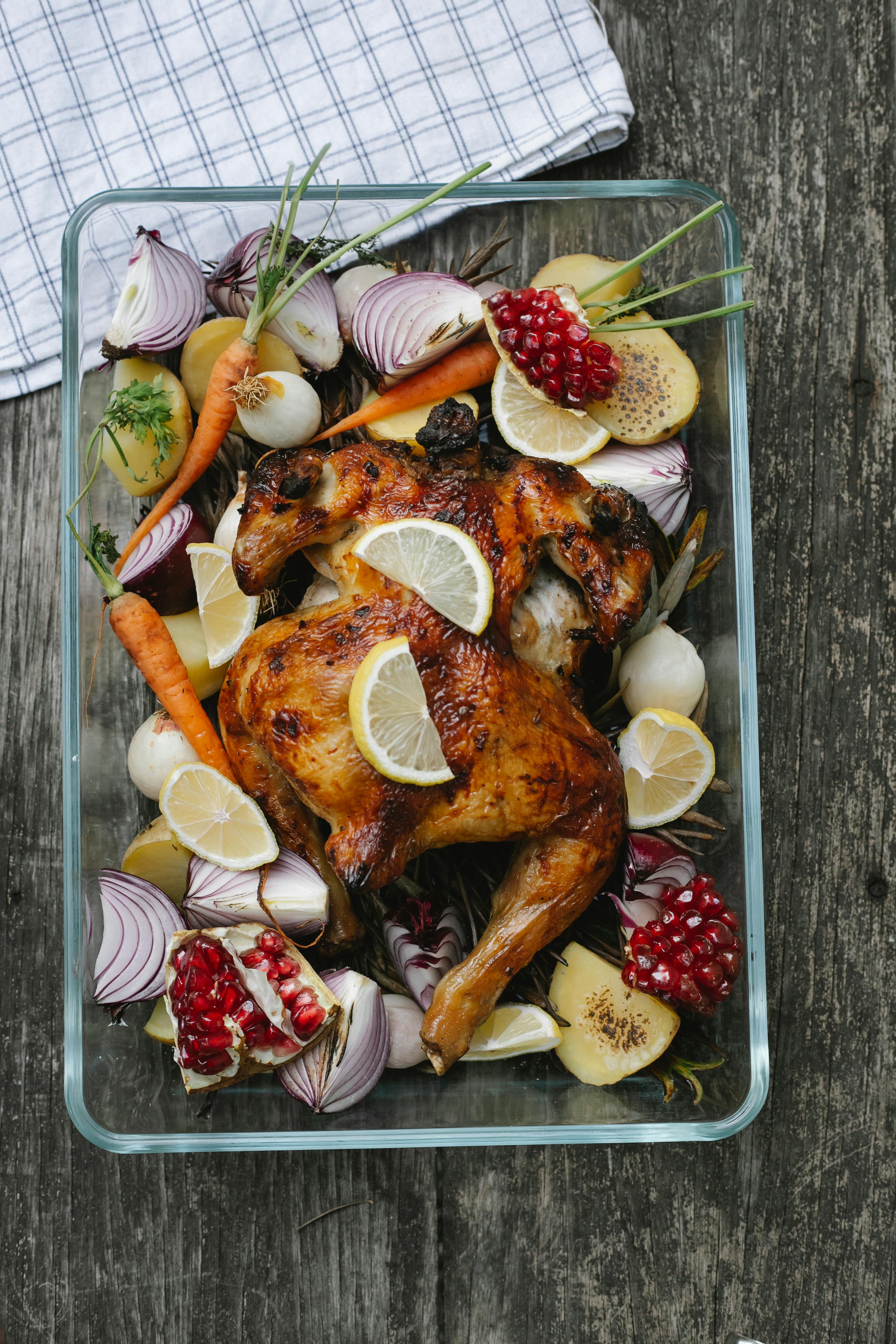 tasty baked chicken with vegetable and fruit mix on table