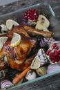 High angle of appetizing baked chicken with pomegranate seeds and lemon slices with red onions in baking dish