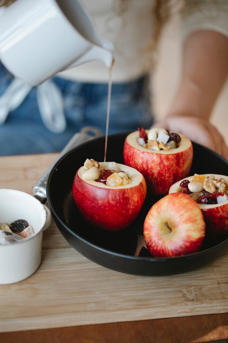 Crop Chef Pouring Honey On Filled Apple At Home