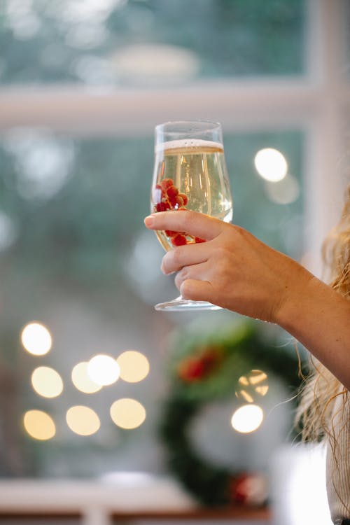 Unrecognizable woman with champagne celebrating Christmas holiday in house